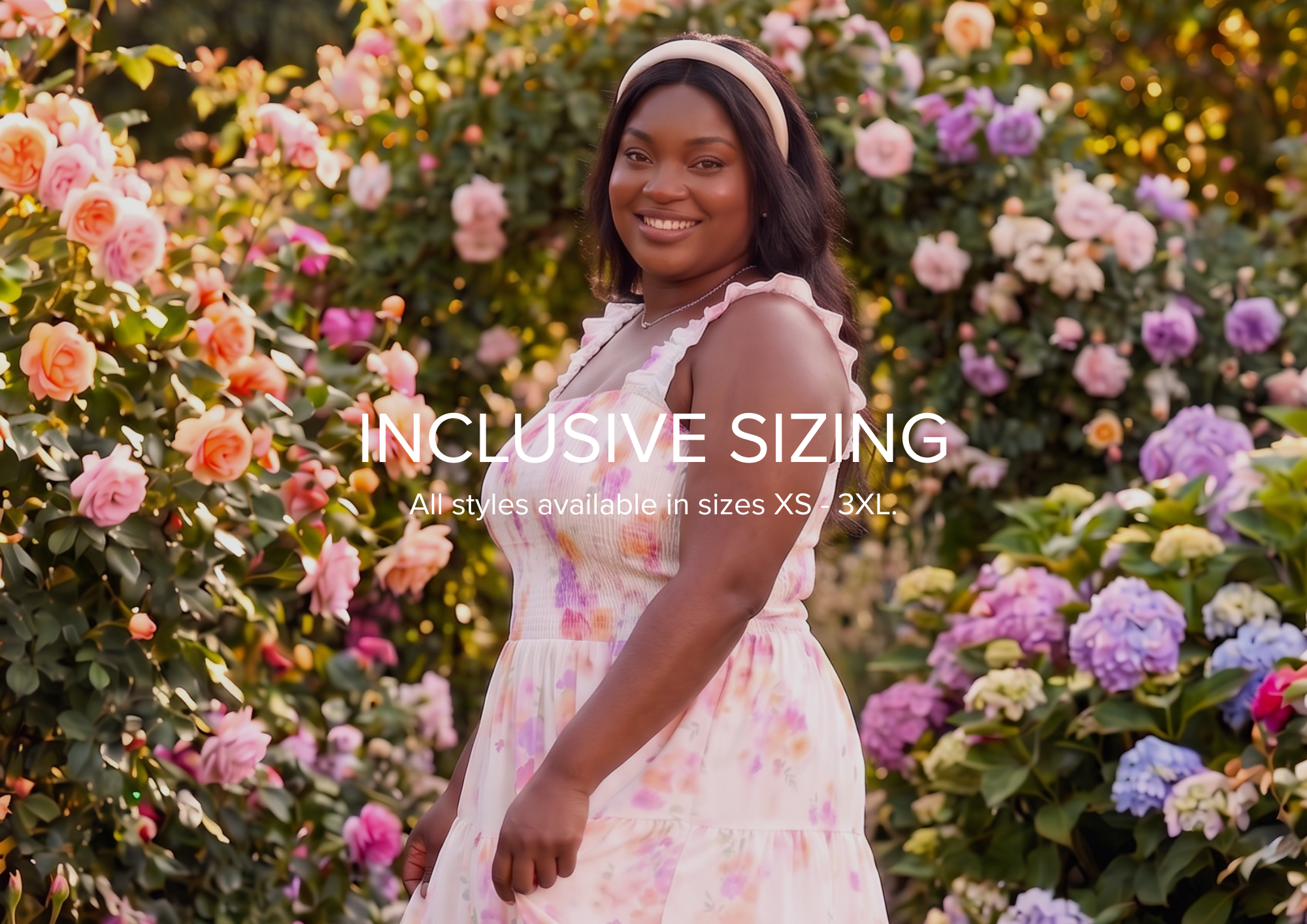 A woman wearing a light pink floral dress and a beige headband stands in a garden of pink and purple flowers, with text overlay reading 'INCLUSIVE SIZING'.