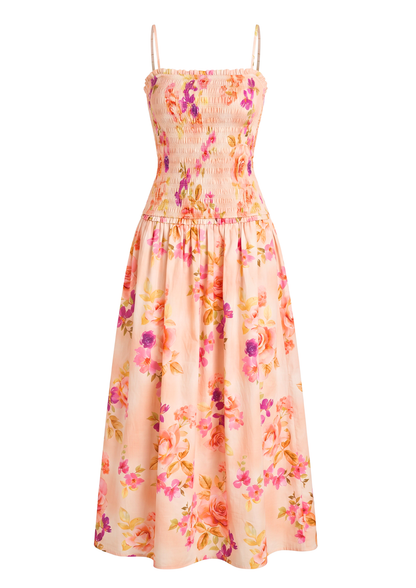 A sleeveless midi dress with thin spaghetti straps, a smocked bodice, and a flared skirt in a peach-pink base color with a vibrant floral print of pink, purple, and orange flowers.